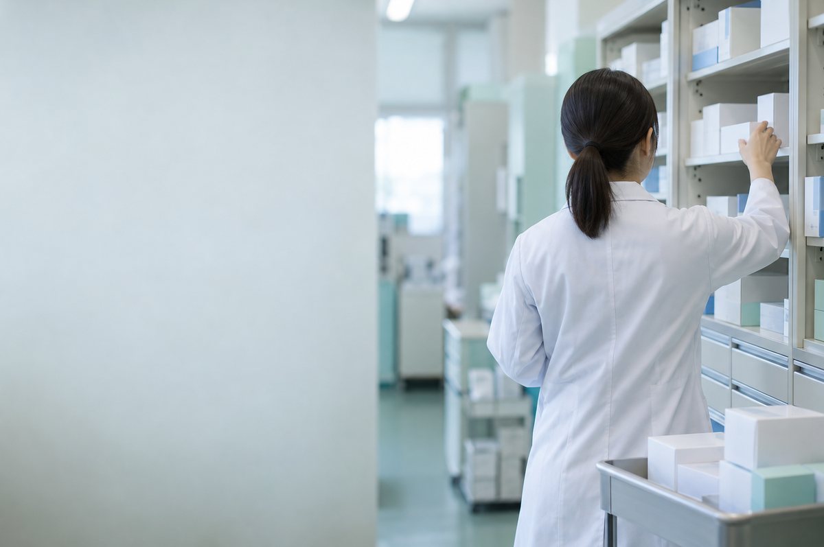 薬局の保管庫に納品された薬箱を収める後ろ姿