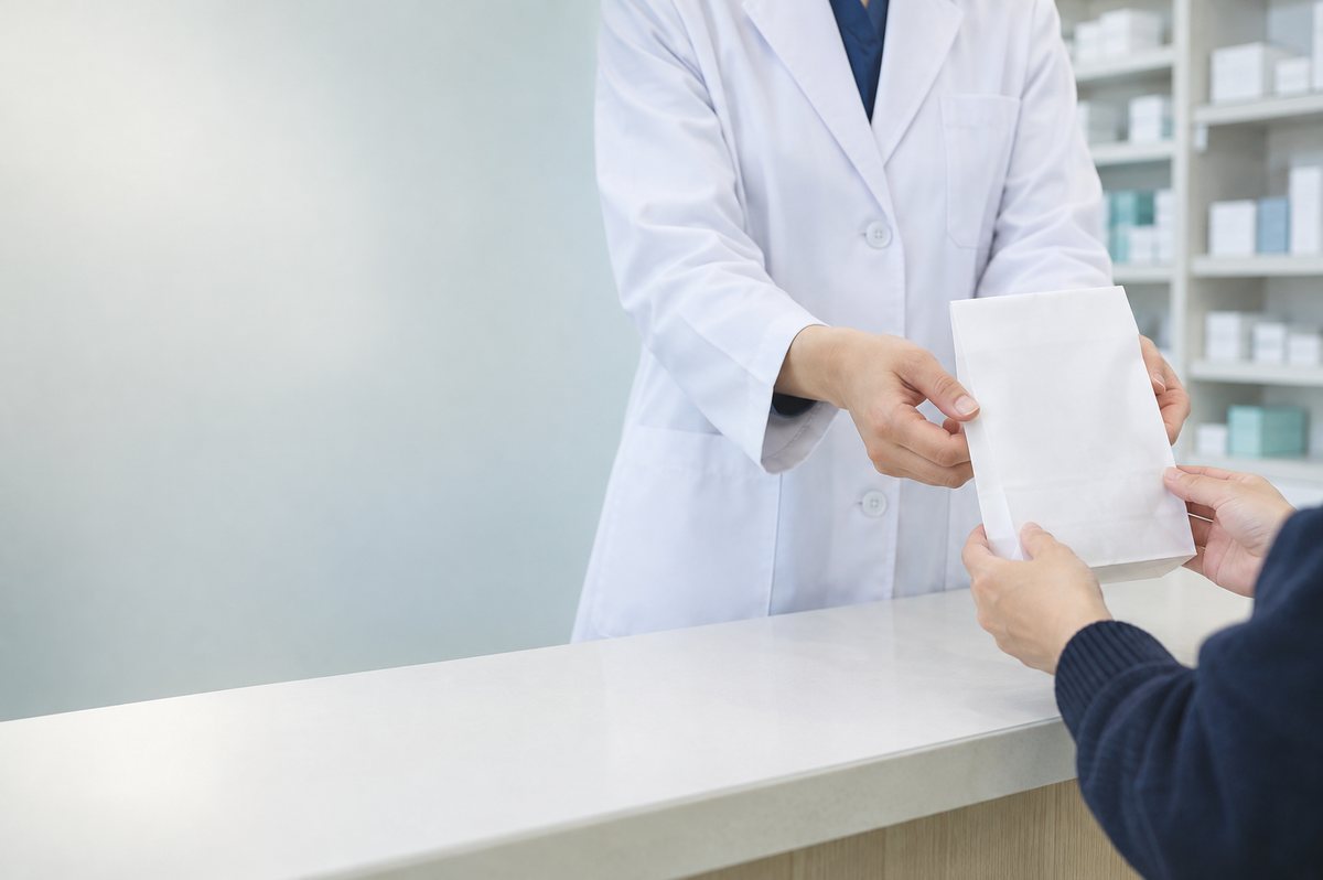 薬局の投薬窓口で薬袋を受け渡す手元