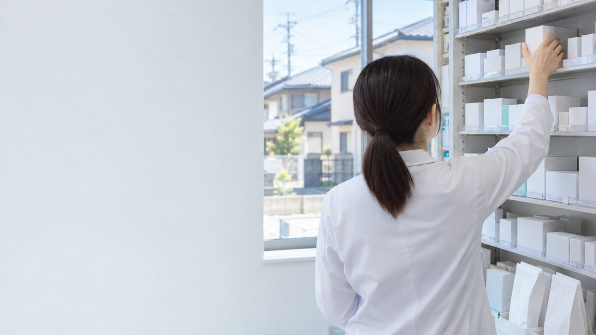 住宅街の薬局で調剤棚から薬を取り出す薬剤師